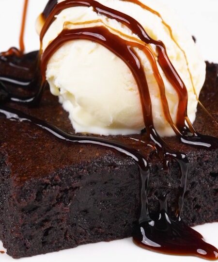 Chocolate Brownies Recipe brownie on plate topped with ice cream and drizzle
