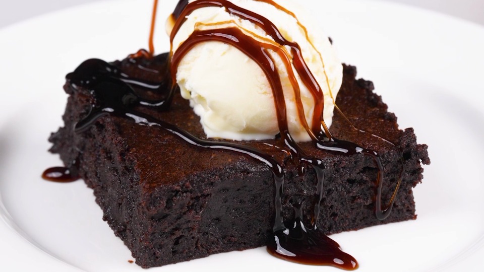 Chocolate Brownies Recipe brownie on plate topped with ice cream and drizzle